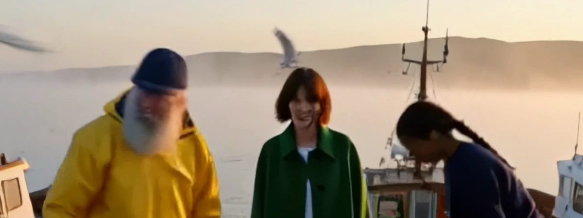 Draft harbour close-up: the bearded fisherman's face is smeared as he moves, Mara's face is soft, and the young woman's face is hidden as she bends towards the crate